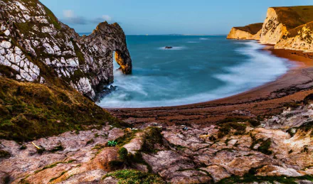 HD desktop wallpaper featuring the iconic Durdle Door cliff arch along the ocean horizon in England, with a sandy beach and natural coastal scenery.