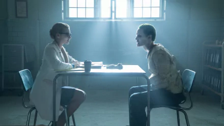 HD desktop wallpaper featuring Margot Robbie as Harley Quinn and Jared Leto as the Joker in a scene from the movie Suicide Squad, depicting an intense conversation in a dimly lit room.