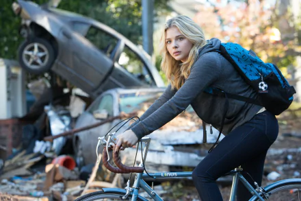 Chloë Grace Moretz as a character from the movie The 5th Wave, riding a bicycle through a post-apocalyptic scene in this 4K Ultra HD PC desktop wallpaper.