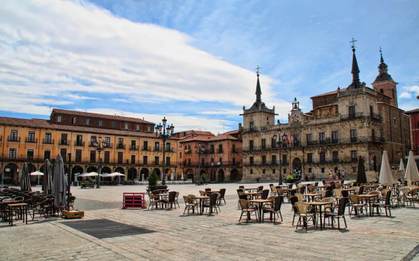 4K Ultra HD image of a historic town hall and surrounding square in Spain, featuring man-made buildings and outdoor seating under a partly cloudy sky.