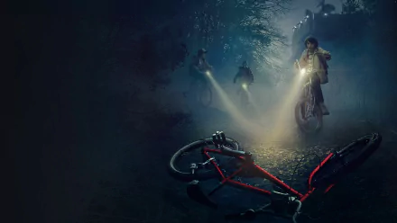 HD desktop wallpaper from the TV show Stranger Things, featuring Lucas Sinclair (Caleb McLaughlin), Dustin Henderson (Gaten Matarazzo), and Mike Wheeler (Finn Wolfhard) biking through a dark, eerie forest.