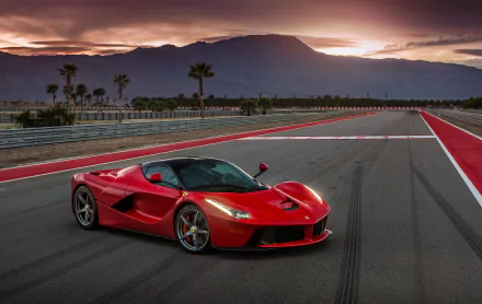 A stunning Ferrari LaFerrari parked on a track at sunset, showcasing its sleek design and vibrant red color against a backdrop of mountains and palm trees. 4K Ultra HD desktop wallpaper.