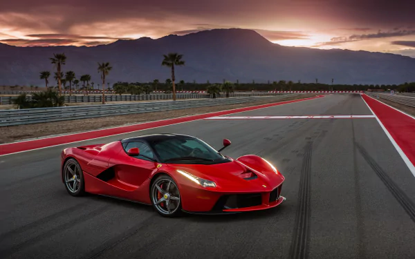 A stunning Ferrari LaFerrari parked on a track at sunset, showcasing its sleek design and vibrant red color against a backdrop of mountains and palm trees. 4K Ultra HD desktop wallpaper.