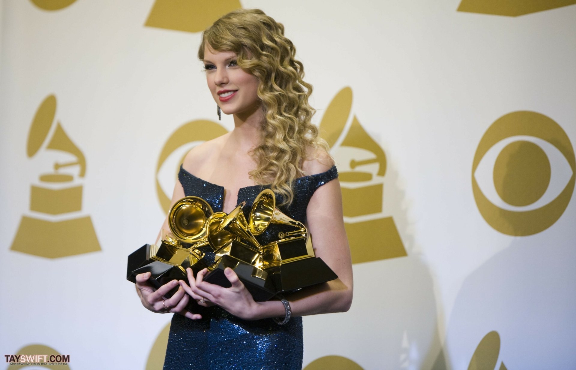 2K Quad HD desktop wallpaper of a female singer with curly blonde hair holding multiple Grammy trophies against a music awards backdrop.