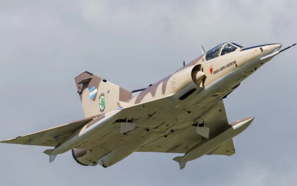 A Dassault Mirage III military aircraft flies dynamically through a cloudy sky, showcasing its sleek design. This high-definition image serves as a striking desktop wallpaper.