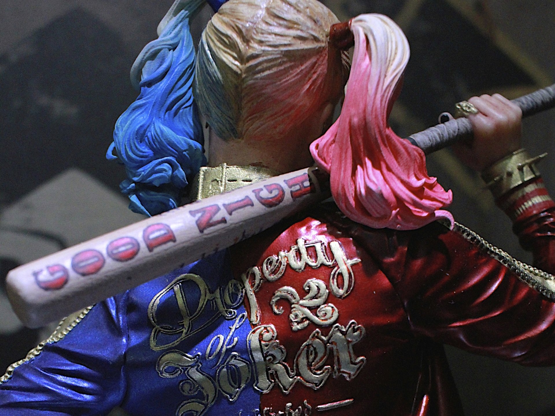 HD PC desktop wallpaper featuring a detailed close-up of comic character Harley Quinn holding her signature baseball bat with colorful blue and pink hair.