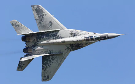 HD desktop wallpaper featuring a Mikoyan MiG-29 military jet fighter in flight against a clear blue sky.