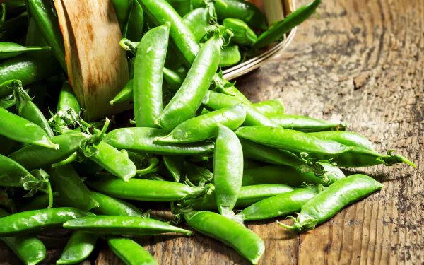 4K Ultra HD PC desktop wallpaper and background: vibrant food close-up of fresh green peas spilling from a wooden basket onto a rustic wood surface.
