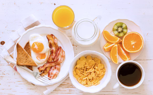 A vibrant 4K Ultra HD still life breakfast featuring orange juice, milk, eggs, bacon, toast, cereal, coffee, and fresh fruit on a white background.