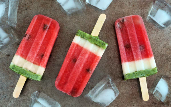 Colorful watermelon-themed ice cream popsicles surrounded by ice cubes, captured in vivid 4K Ultra HD as a refreshing summer food desktop wallpaper.