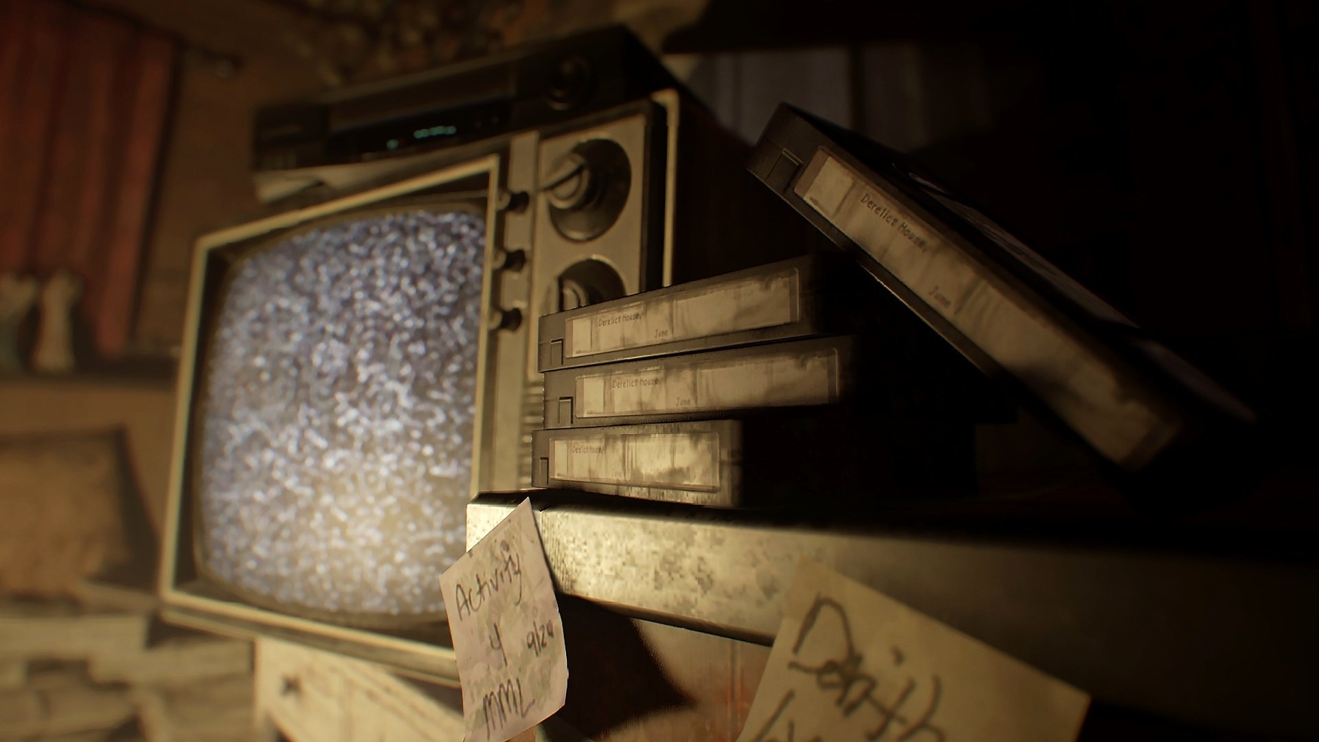 HD PC desktop wallpaper: moody Resident Evil 7: Biohazard scene — dusty CRT TV showing static, stacked VHS tapes and handwritten notes in a dim, decaying room.