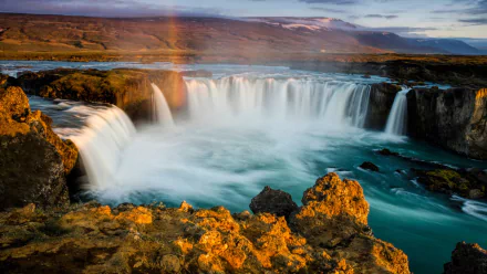 HD desktop wallpaper featuring the stunning Goðafoss waterfall in Iceland, showcasing vibrant natural colors and flowing water in a serene landscape.