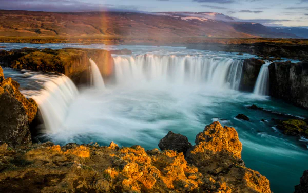 HD desktop wallpaper featuring the stunning Goðafoss waterfall in Iceland, showcasing vibrant natural colors and flowing water in a serene landscape.