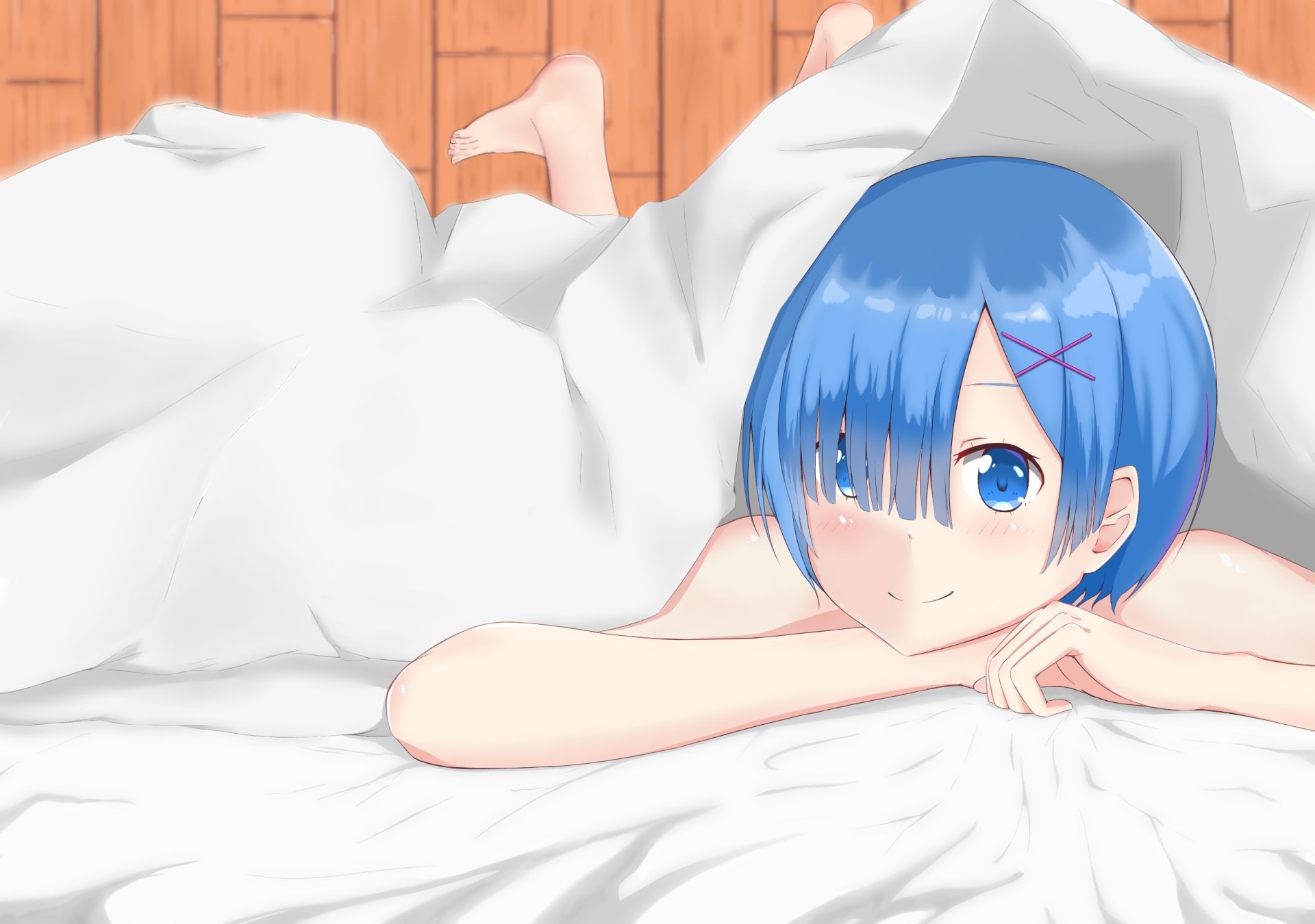A close-up of Rem from Re:ZERO - Starting Life in Another World, featuring her short blue hair and blue eyes, relaxing under a blanket in a cozy setting. HD wallpaper.