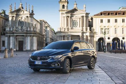 A sleek black Fiat Tipo car parked on a historic city square with classic European architecture in the background, captured in stunning 4K Ultra HD detail.