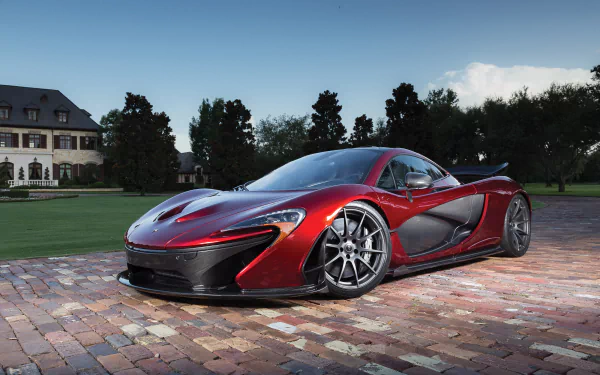 A striking red McLaren P1 supercar parked on a cobblestone driveway, showcased in a 4K Ultra HD desktop wallpaper with a scenic background.