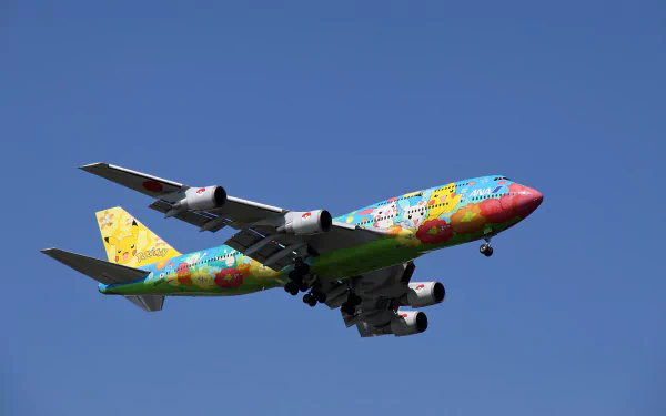 A colorful Boeing 747 airplane decorated with Pokémon characters soars against a clear blue sky, creating a vibrant and playful desktop wallpaper scene.