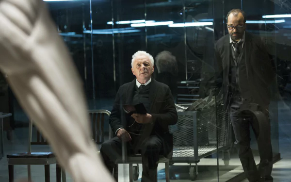Bernard Lowe and Robert Ford, portrayed by Jeffrey Wright and Anthony Hopkins, sit in a reflective, high-tech environment from the TV show Westworld. An intriguing moment captured in HD wallpaper.