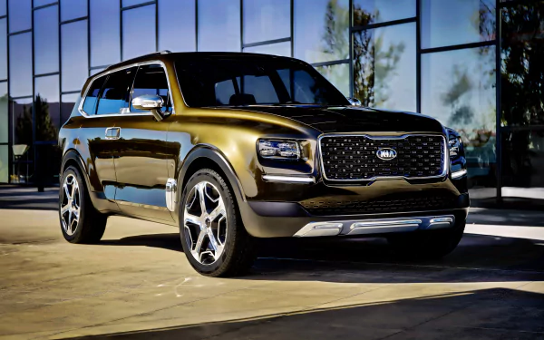 2K Quad HD desktop wallpaper: metallic Kia Telluride SUV parked before a glass building, shown in a front three-quarter view.