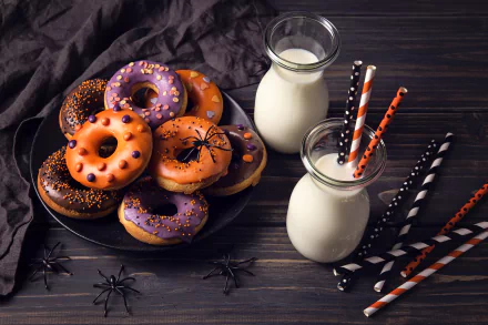 A 4K Ultra HD PC wallpaper showing Halloween-themed doughnuts with orange and purple icing, festive sprinkles, black plastic spiders, and two bottles of milk with striped straws.