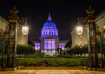 Night view of San Francisco City Hall illuminated in purple light, framed by ornate lanterns and gates, captured in high-definition for a striking desktop wallpaper.