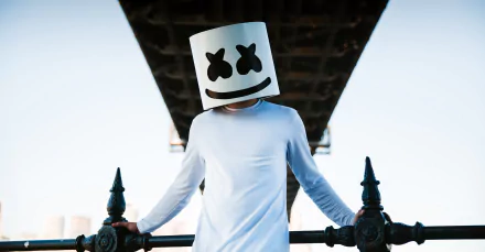 HD desktop wallpaper featuring Marshmello, the DJ, posing under an urban bridge with his signature helmet and a white outfit.
