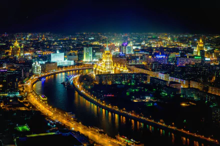 A stunning aerial view of Moscow at night, showcasing the illuminated cityscape along the river horizon, highlighting the vibrant lights of this man-made marvel in Russia.