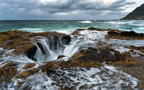 4K Ultra HD desktop wallpaper of Oregon’s rugged ocean coastline with waves crashing into a rocky sea horizon under a cloudy sky.