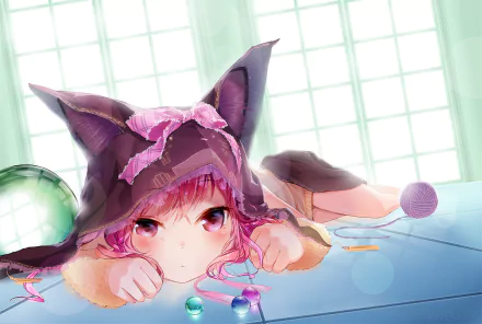 An anime girl with nekomimi (cat ears) lies on a table, surrounded by yarn balls and a green decorative sphere. The image is a high-definition desktop wallpaper with a background of a bright, white window.