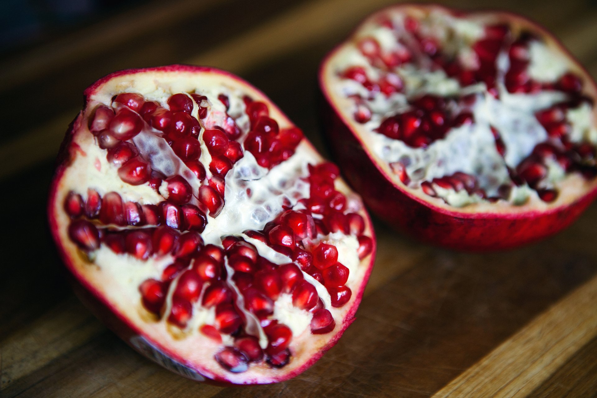 HD PC desktop wallpaper featuring a close-up of a halved pomegranate with vibrant red seeds and rich texture, highlighting fresh fruit and food detail.
