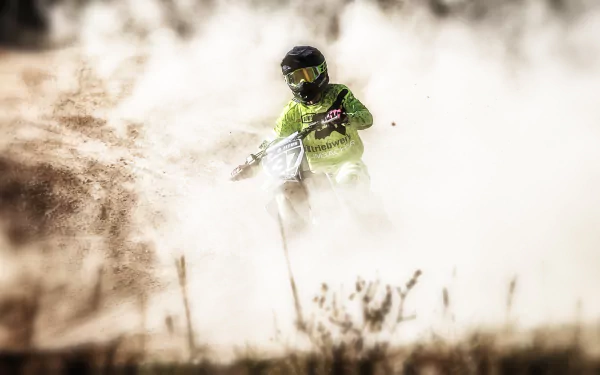A motocross rider maneuvers through a cloud of dirt, showcasing the excitement of the sport in this high-definition desktop wallpaper and background.
