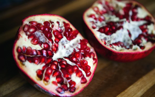 HD PC desktop wallpaper featuring a close-up of a halved pomegranate with vibrant red seeds and rich texture, highlighting fresh fruit and food detail.