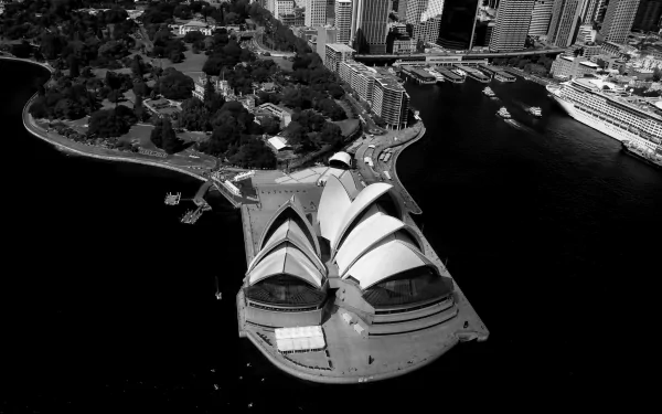 Aerial black and white view of Sydney Opera House and Circular Quay in Sydney Harbour, Australia, showcasing iconic man-made structures against the cityscape.