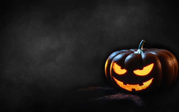 A glowing jack-o'-lantern with a sinister face illuminates a dark background, captured in 4K Ultra HD as a Halloween-themed PC desktop wallpaper.