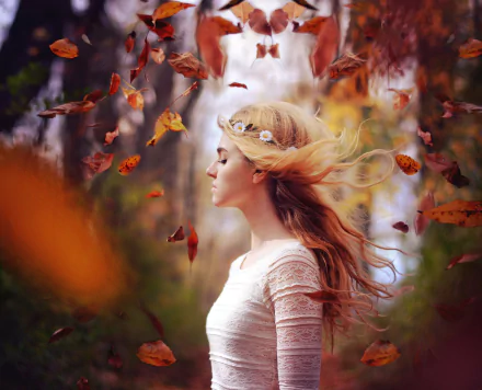 A blonde woman with flowing hair stands amidst swirling fall leaves, captured in a moody, shallow depth of field for an HD desktop wallpaper.