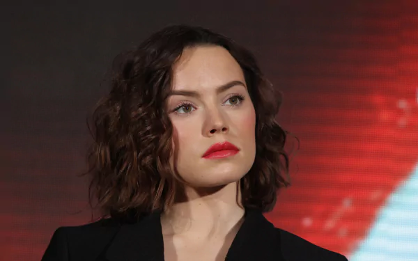 HD wallpaper of English actress Daisy Ridley with brunette hair, hazel eyes, and bold red lipstick against a dark background.