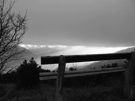 Black & white photography of a wooden bench overlooking foggy mountains, captured in 4K Ultra HD for PC desktop wallpaper and background.
