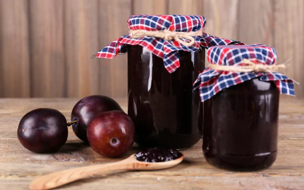 4K Ultra HD PC desktop wallpaper and background: jars of homemade plum jam with whole plums and a spoon on a rustic wooden table.