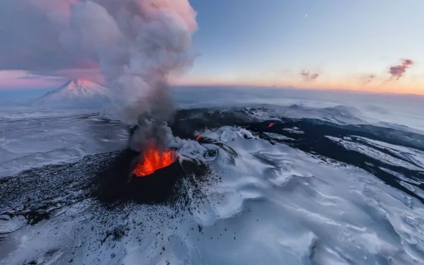 A stunning aerial view of a volcano erupting with glowing lava amidst a snowy, icy winter landscape, captured as an HD desktop wallpaper and background. Smoke billows into the sky, painting a dramatic scene.