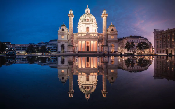 Night view of Karlskirche in Vienna, Austria, beautifully reflected in calm water, showcasing its iconic dome and baroque architecture.