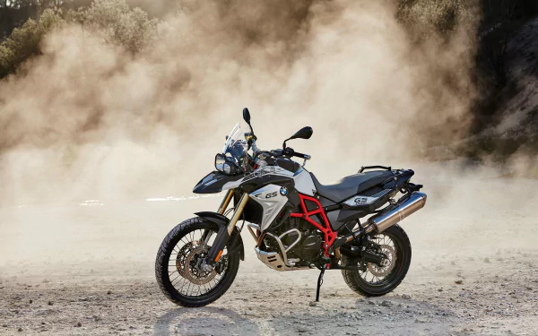 HD PC desktop wallpaper featuring a BMW F800GS motorcycle parked on dusty terrain with a dramatic dust cloud background.
