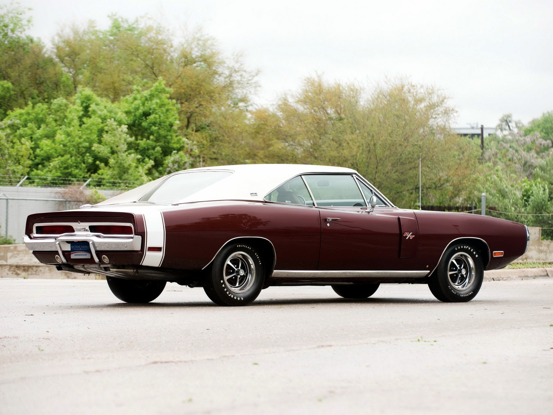 HD desktop wallpaper featuring a classic maroon Dodge Charger RT SE parked outdoors with greenery in the background, highlighting the iconic muscle car design.