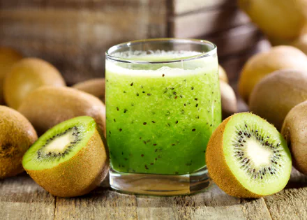 A vibrant glass of kiwi juice surrounded by whole and halved kiwifruit, captured in sharp detail as a 4K Ultra HD desktop background.