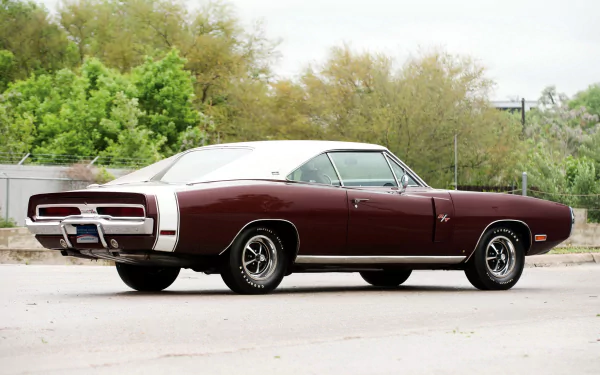 HD desktop wallpaper featuring a classic maroon Dodge Charger RT SE parked outdoors with greenery in the background, highlighting the iconic muscle car design.
