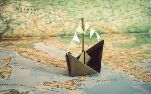 Origami paper boat displayed on a detailed map, blending man-made craftsmanship with geographical elements in an HD desktop wallpaper background.