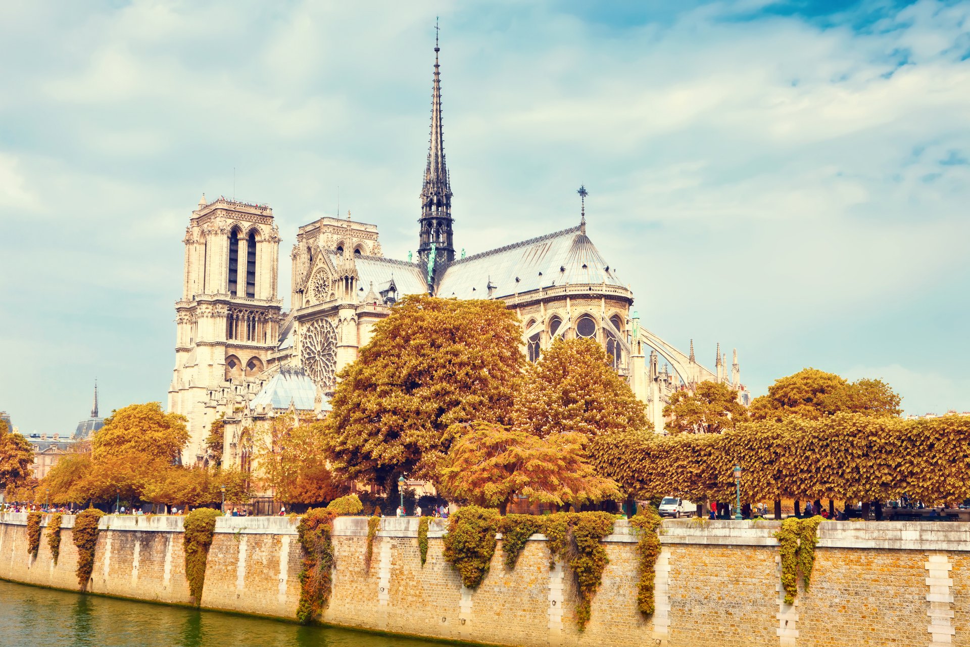 Notre-Dame de Paris cathedral on the Seine with autumn trees and blue sky — Parisian religious architecture rendered as a 5K Ultra HD PC desktop wallpaper.