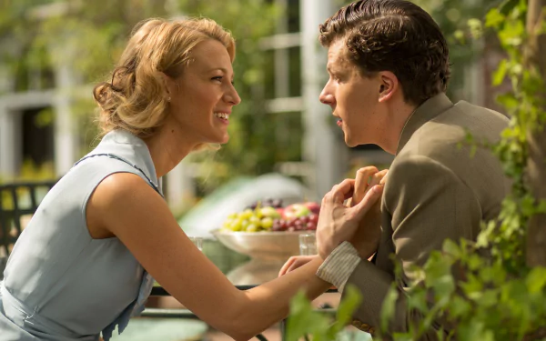 Sunlit outdoor café scene of two actors smiling and holding hands across a table, a still from the movie Café Society rendered as a 4K Ultra HD PC desktop wallpaper.