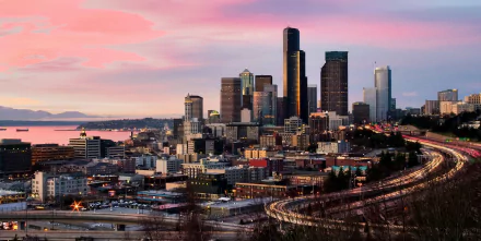 HD desktop wallpaper featuring the Seattle skyline at dusk with a vibrant pink sky and city lights beginning to glow.