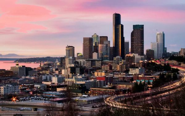 HD desktop wallpaper featuring the Seattle skyline at dusk with a vibrant pink sky and city lights beginning to glow.