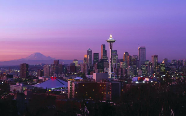 HD wallpaper featuring the Seattle skyline at dusk with the Space Needle prominent against a purple sky and Mount Rainier in the background.
